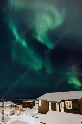 Northern lights above snow-covered houses at night photo