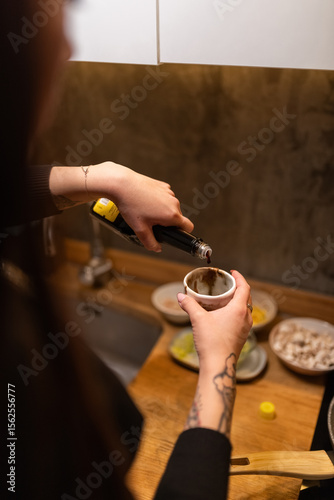 Woman pouring teriyaki sauce into cup