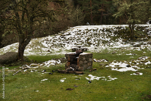 Snow covered stone picnic table, first snowfall of the season in the mountains
