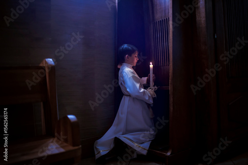 Fotografie Catholic boy holding a candle, confessing before his first communion