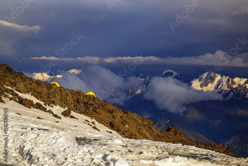 Yellow tents on snowy mountain slopes during sunset.