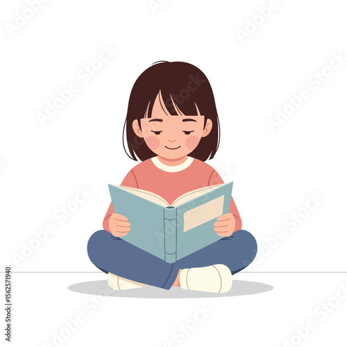 A young girl sits cross-legged, engrossed in reading a book.