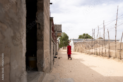 Senegalese woman walking in a rural village carrying something