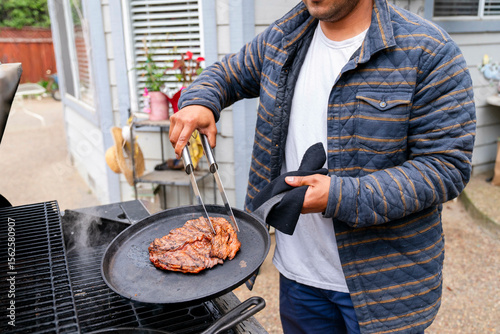man using outdoor grill steak