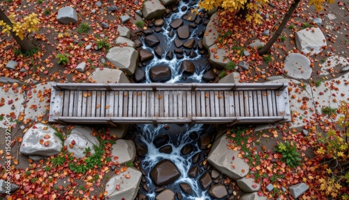 Wooden Bridge Over a Tranquil Stream Surrounded by Colorful Autumn Leaves and Rocks