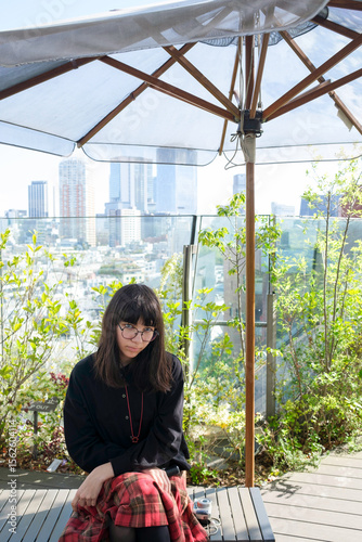 Young Woman sitting on a rooftop terrace surrounded by greenery