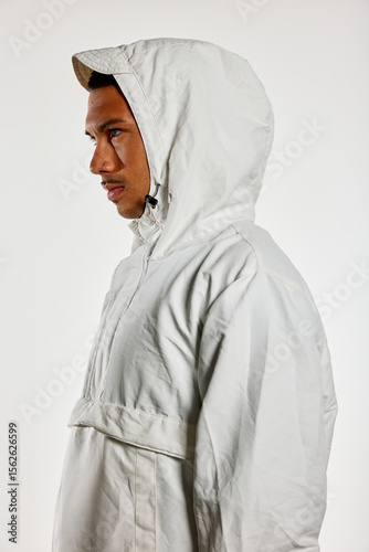 Male model wearing hooded jacket in profile indoors