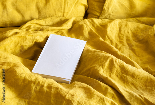 Empty white book cover mockup on distressed bedding background