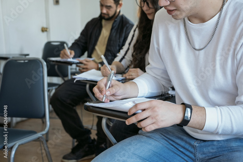 Young adults writing at desks in a classroom