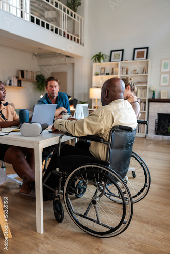 Diverse team meeting, wheelchair user included, in modern office