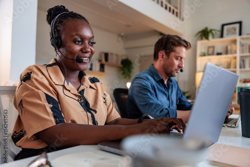 Two people working from home with headsets and laptops. photo
