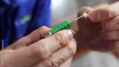 Cleaned and stripped fiber optic cable being inserted and secured into an APC (angled physical contact) connector with a click-lock closure 