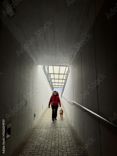 Backlit portrait of woman entering a dark tunnel alone with her dog 