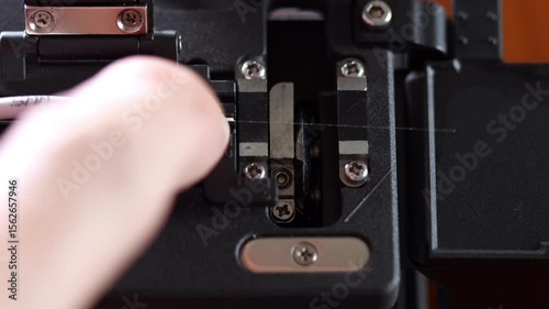 Close up shot of fiber core being inserted and precisely cleaved inside a fiber cleaver