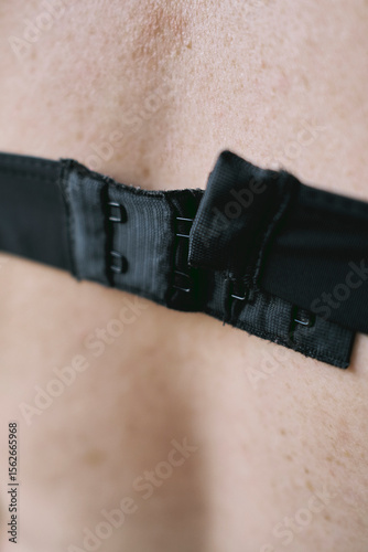 Close-up view of a black strap fastening on bare skin