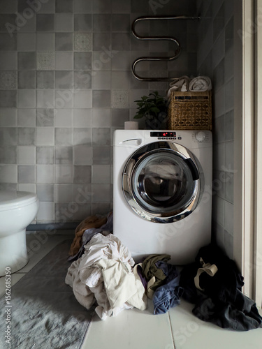 Washing machine with a pile of dirty clothes in the bathroom