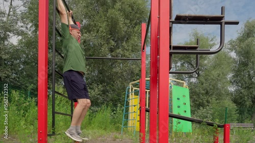 Active elderly man exercising outdoors. Abdominal press exercise.