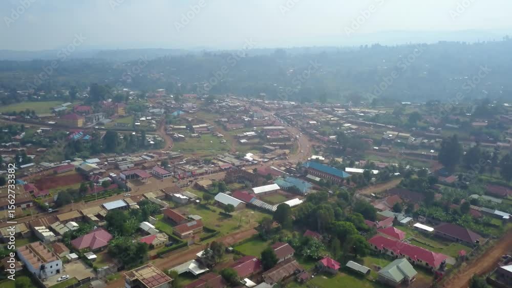 Drone pullout over Kapchorwa Town in Eastern Uganda showing the B1 road, Kapchorwa District HQ, Kapchorwa Modern Market, schools and churches with hills and haze in background.