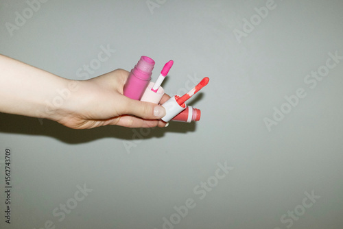 Hand holding pink & coral liquid blushes lip gloss make up products