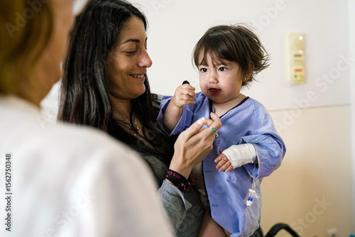 Mother comforting her sick toddler daughter in hospital room