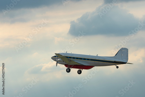 Military plane flying through the sky and clouds on nature background