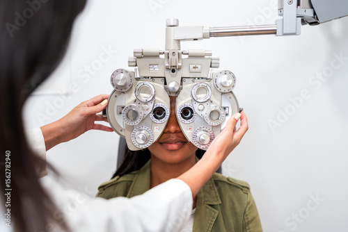 Optician examining patient eyesight with phoropter during eye exam