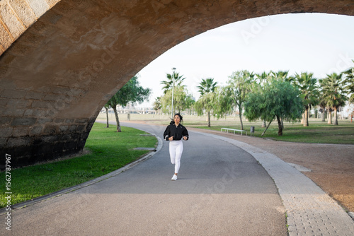 Latina woman running outdoors in a green park