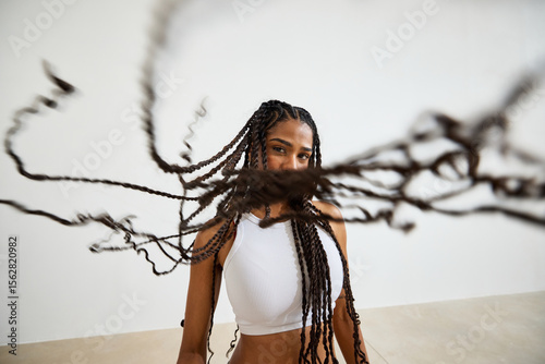 Person with long braids showcases a dynamic hairstyle in a studi