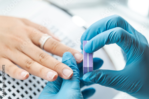 Professional Manicure Process with Gloved Hands and Buffing Block