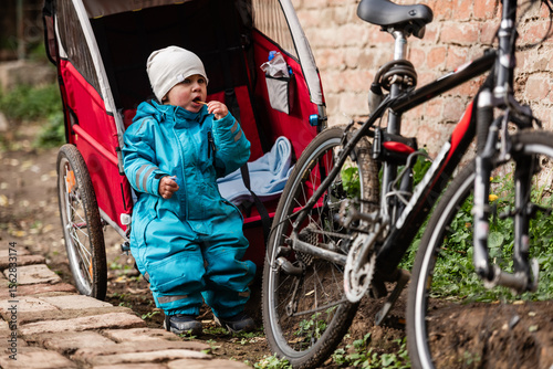 Toddler eating snack next to bike trailer and bicycle