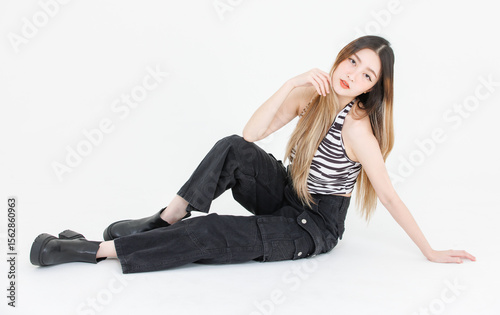Full length of trendy fashion asian attractive pretty young woman model poses confidence wear zebra print halter top, black cargo pants, look at camera streetwear style sitting white background studio