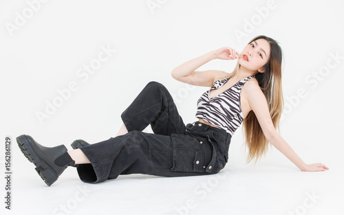 Full length of trendy fashion asian attractive pretty young woman model poses confidence wear zebra print halter top, black cargo pants, look at camera streetwear style sitting white background studio