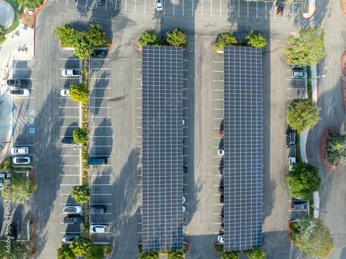 Aerial view of solar panels installed as shade roof over parking lot for parked cars. Photovoltaic technology integrated in urban infrastructure. High quality photo