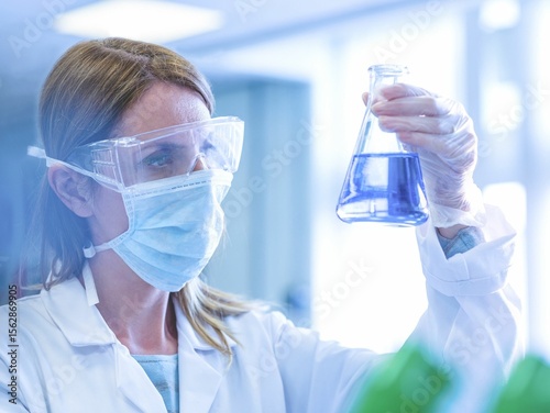 Female scientist looking at reaction happening in flask