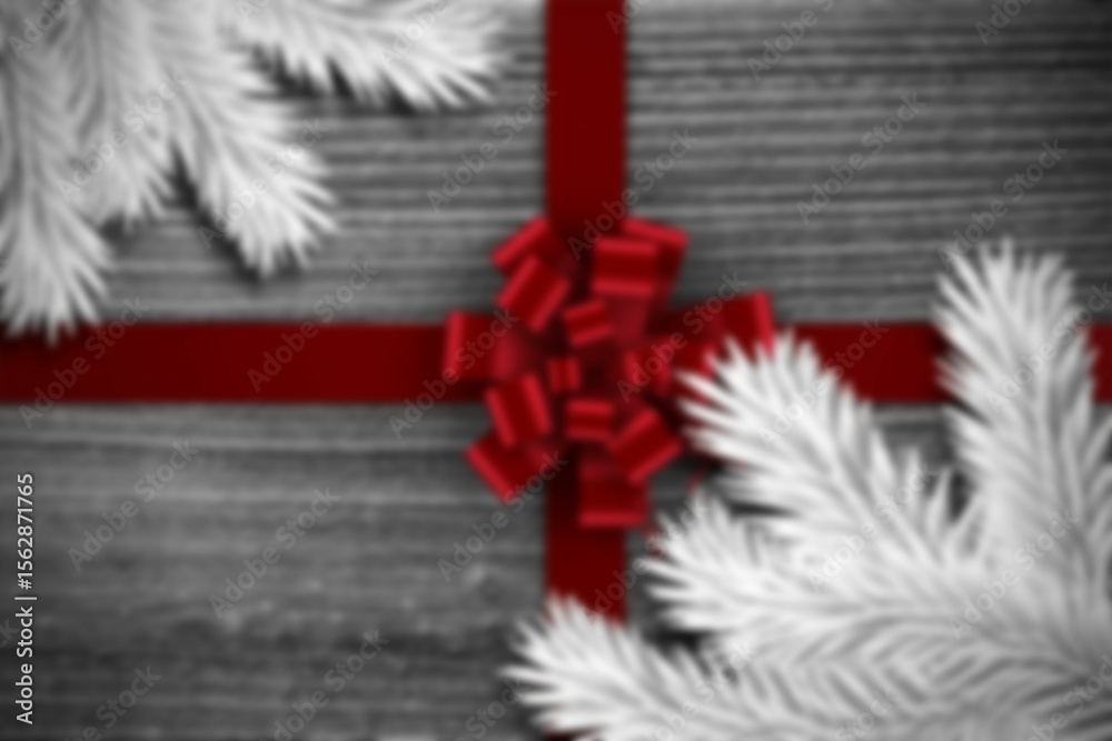 Fototapeta premium Flat-lay design is featuring red satin ribbon crossing grey wood planks with white conifer branches