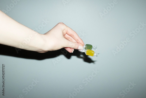 Hand holding colourful wrapped sugar sweet candy with flashlight
