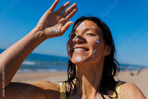Woman applying sunscreen enjoying summer sun at beach