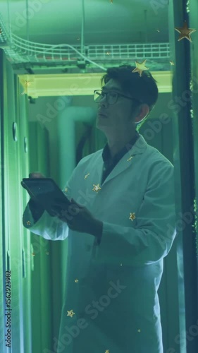 Examining data on tablet, scientist in lab coat in green-lit corridor