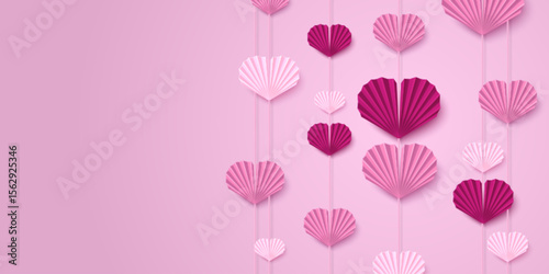 Pink paper heart garland backdrop with hanging folded fan decorations in light pink and magenta colors. Valentine Day romantic display with multiple strings of origami style for wedding or party decor