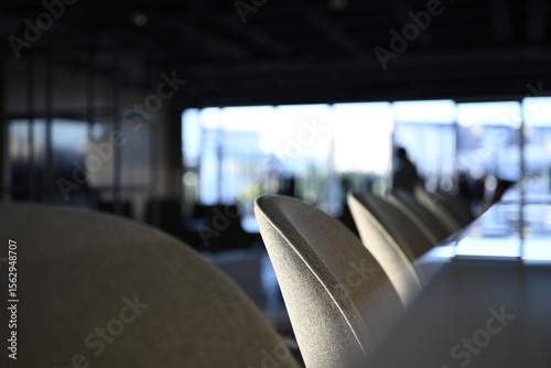 Bar stools and marble bar counter in a modern office interior with shallow depth of field and windows showing in the background