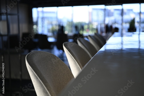 Bar stools and marble bar counter in a modern office interior with shallow depth of field and windows showing in the background