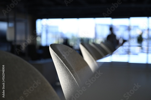 Bar stools and marble bar counter in a modern office interior with shallow depth of field and windows showing in the background