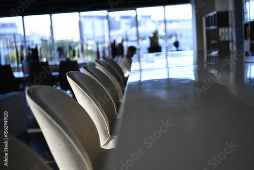 Bar stools and marble bar counter in a modern office interior with shallow depth of field and windows showing in the background