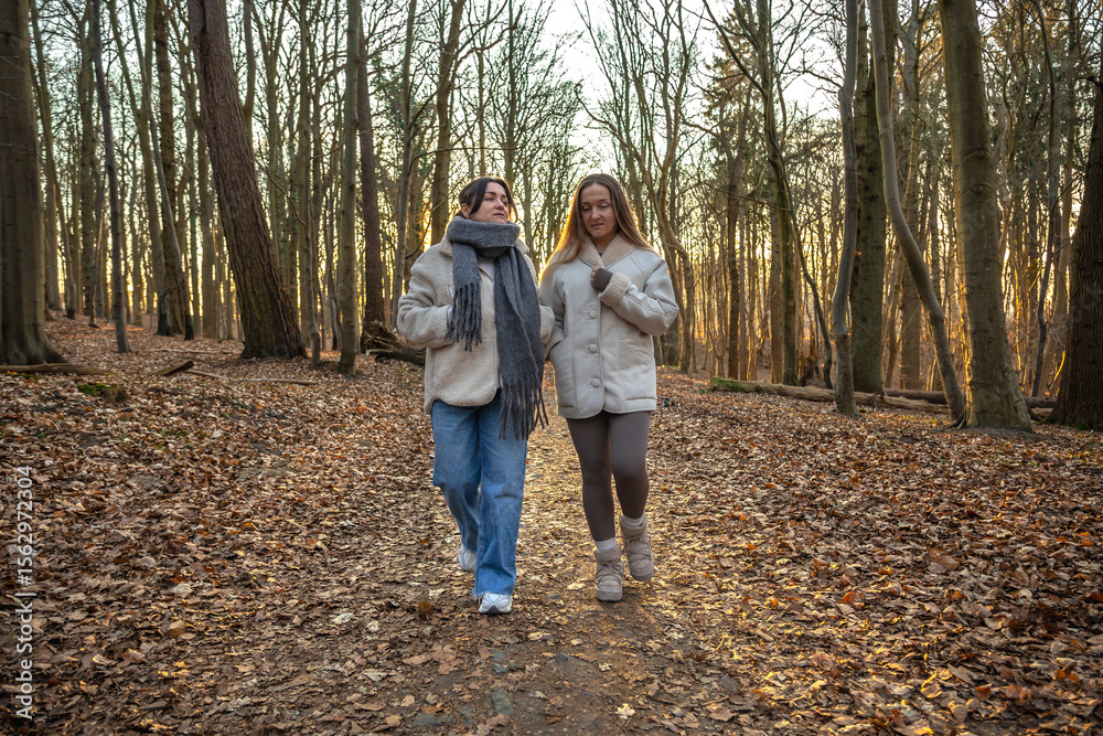 Fototapeta premium Two female friends on a walk in the forest. Friends walking through the forest. People in nature.