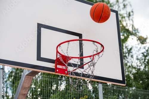 Street basketball action  ball flying toward hoop with metal chain net
