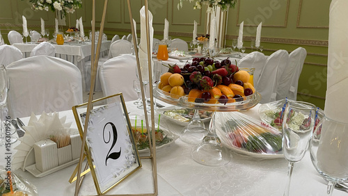 Elegantly arranged dining table for a celebration event, featuring a fruit platter, fresh salads, and decorative table settings. Perfect for weddings, parties, or corporate gatherings