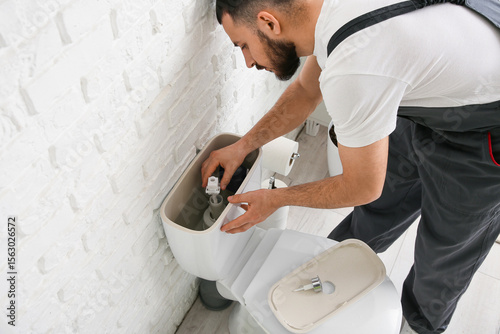 Male plumber repairing toil...