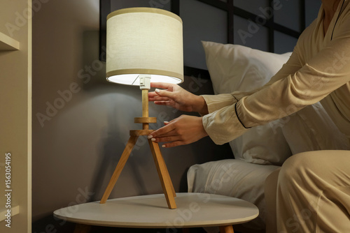 Woman turning off lamp on b...