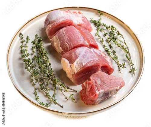 Fresh raw pork fillet medallions with sprigs of thyme on a rustic ceramic plate, highlighting tender meat cuts with natural textures and pink hues, ideal for culinary preparation and meat selection