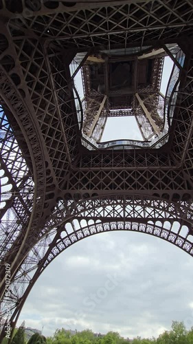 Metal structure of the Eiffel Tower rising towards a cloudy sky